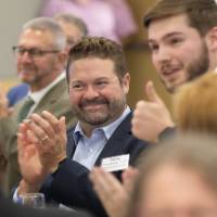 Two gentleman listening to speaking and smiling